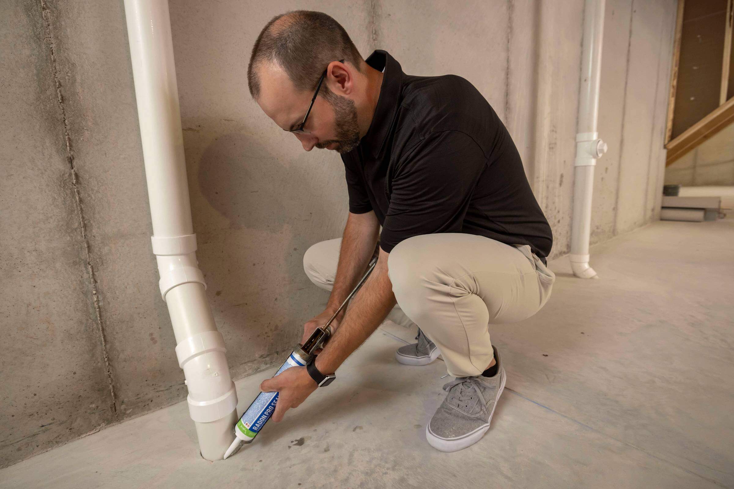 A man working on installing a radon mitigation system in the interior of a home.