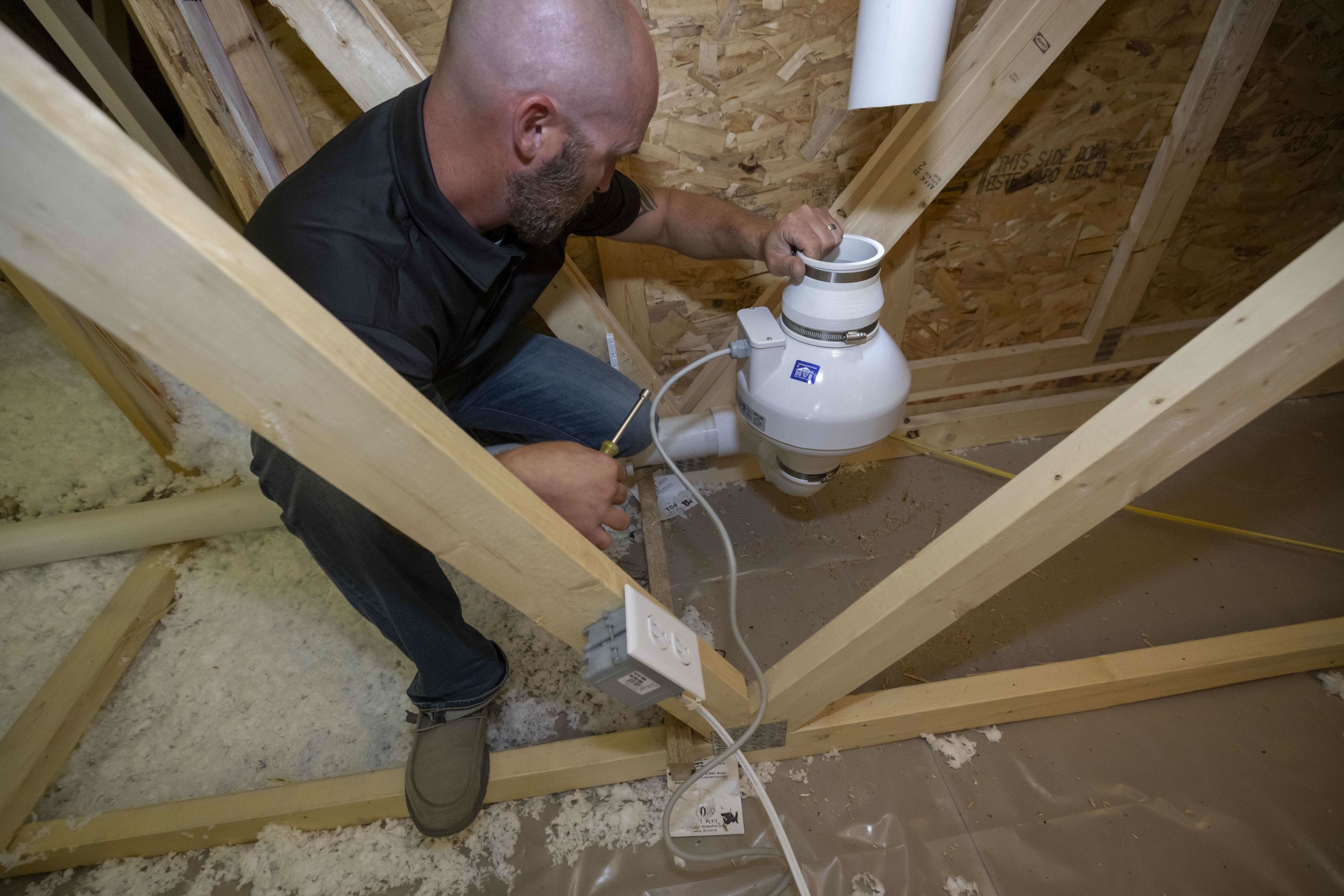 A man adjusting a radon mitigation system in someone's home interior.