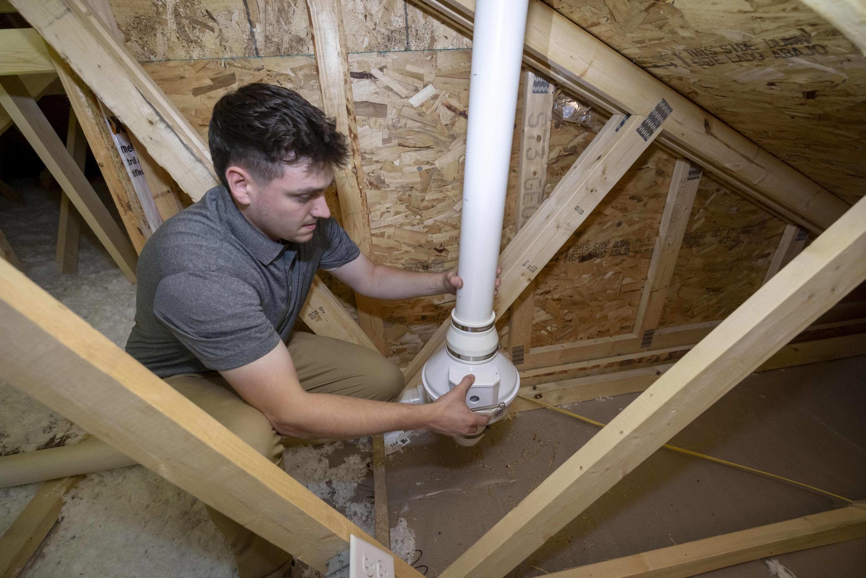 A man adjusting a radon mitigation system in someone's home interior.