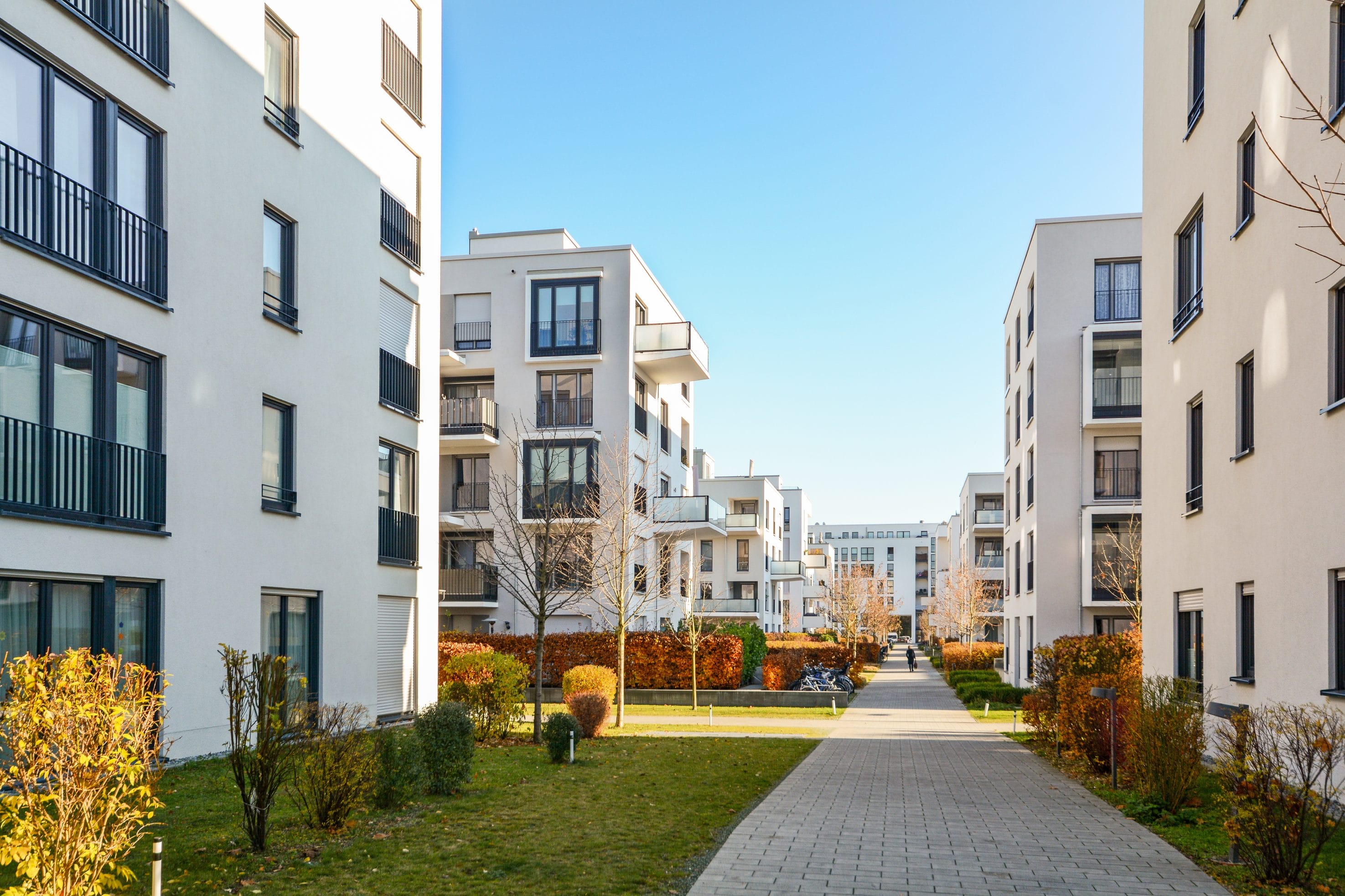 An exterior view of multiple apartment buildings with a sidewalk between them.